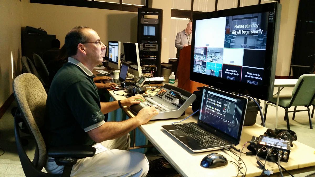 A man is sitting at a desk in front of a computer monitor.