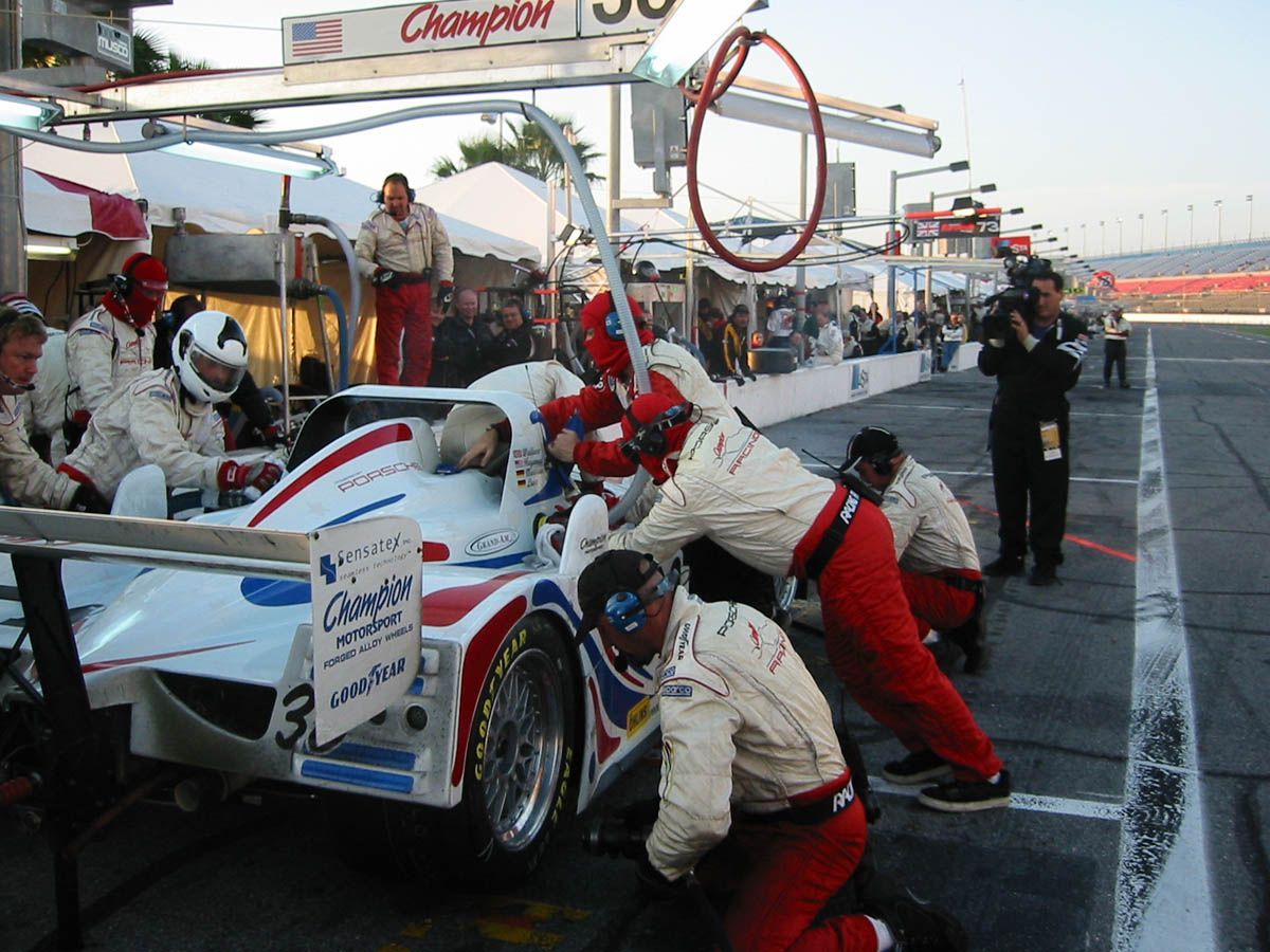 A group of people working on a race car with a champion sign in the background