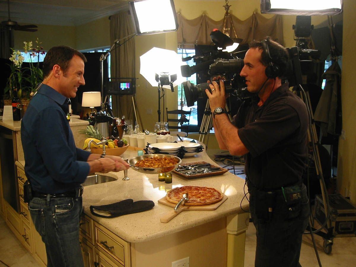 A man is being interviewed by a cameraman in a kitchen