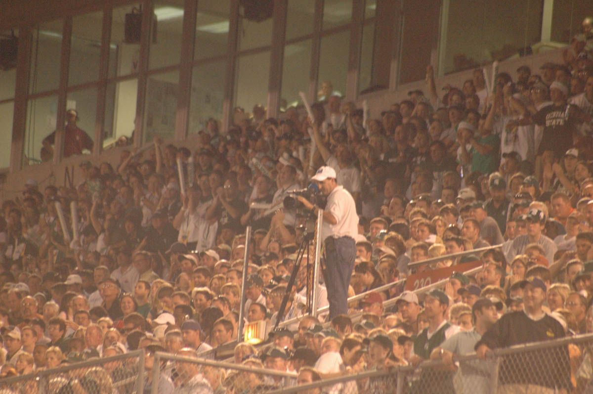 A man is taking a picture of a crowd of people in a stadium.