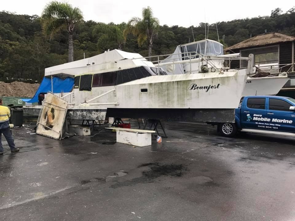 A Boat Is Sitting in A Parking Lot Next to A Truck — Don's Marine Repairs in Gosford, NSW