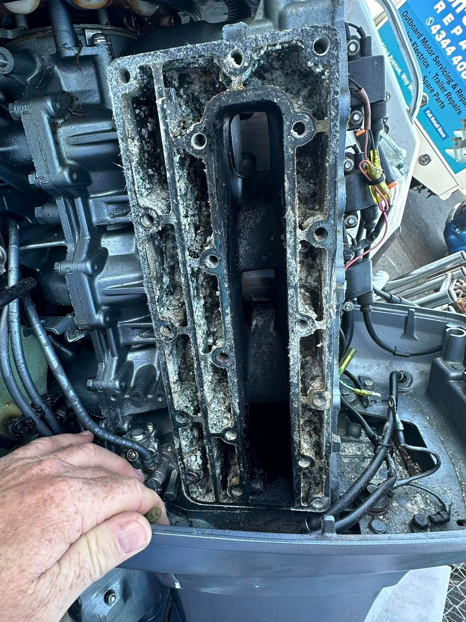 A Person Is Cleaning the Inside of A Boat Engine — Don's Marine Repairs in Woy Woy, NSW