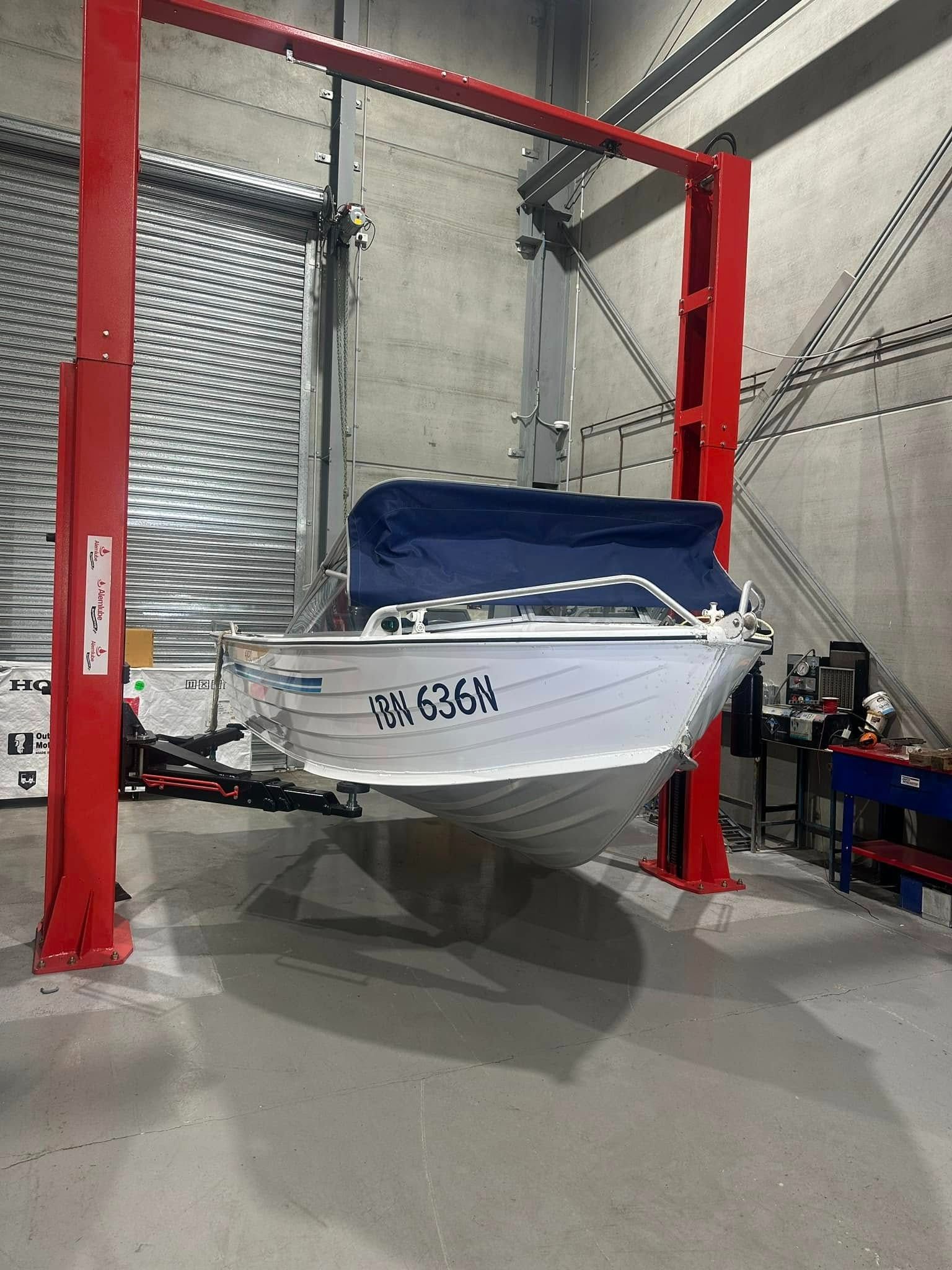 A Boat Is Sitting on Top of A Red Lift in A Garage — Don's Marine Repairs in Umina, NSW
