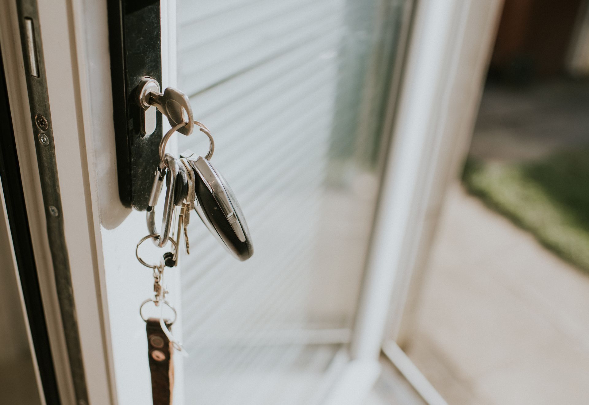 A set of keys hanging from a lock in a white door frame, viewed from an angle.