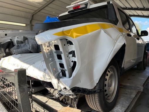 A white truck with a yellow stripe on the side is sitting in a garage.