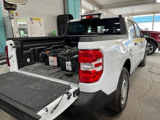 A white truck is parked in a garage with its bed open.
