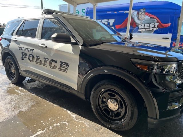 A black and white police car is parked in front of a best car wash