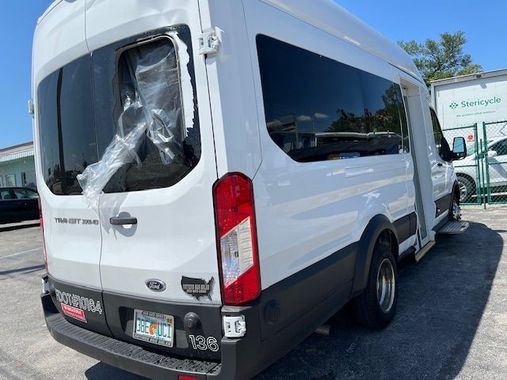 A white van with a broken window is parked in a parking lot.
