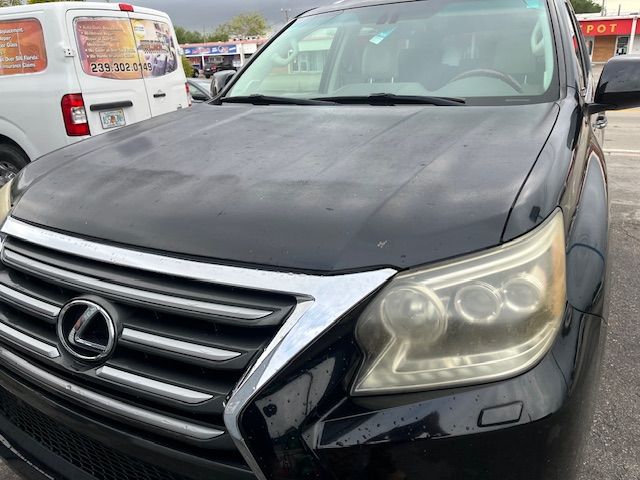 A black lexus is parked in a parking lot next to a white van.