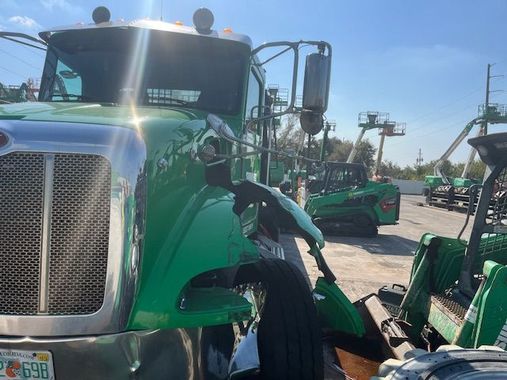 A green truck is parked next to a green tractor.