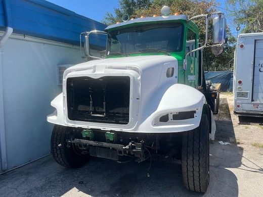 A green and white truck is parked in front of a building.