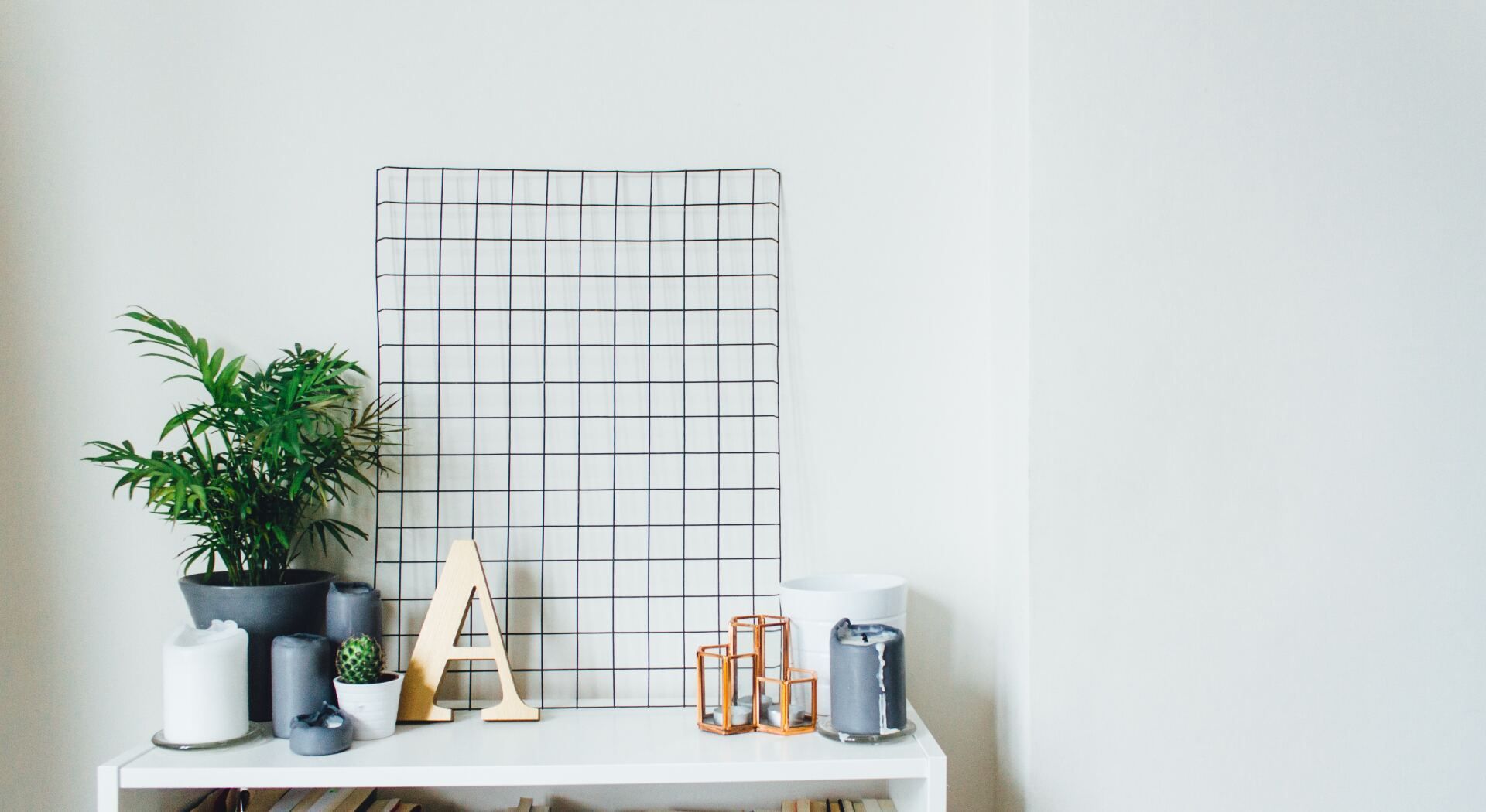 A white shelf holds a green plant, a decorative wooden letter 