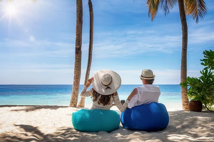 Un hombre y una mujer están sentados en pufs en la playa.
