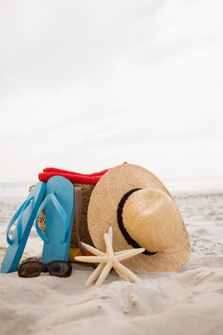 Un sombrero, chanclas, gafas de sol y una estrella de mar están en la playa.