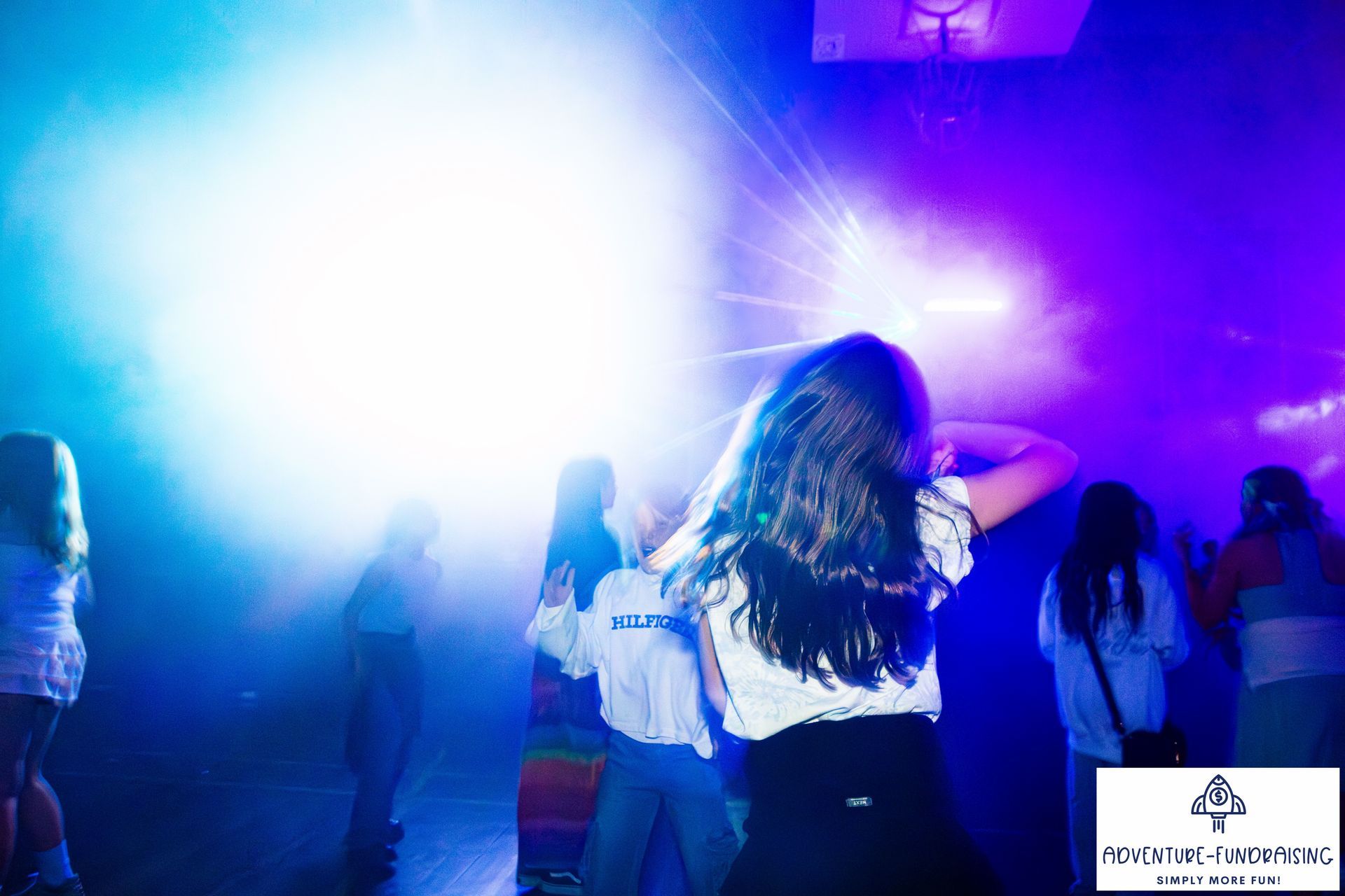 People dancing in a room with blue and white stage lighting.
