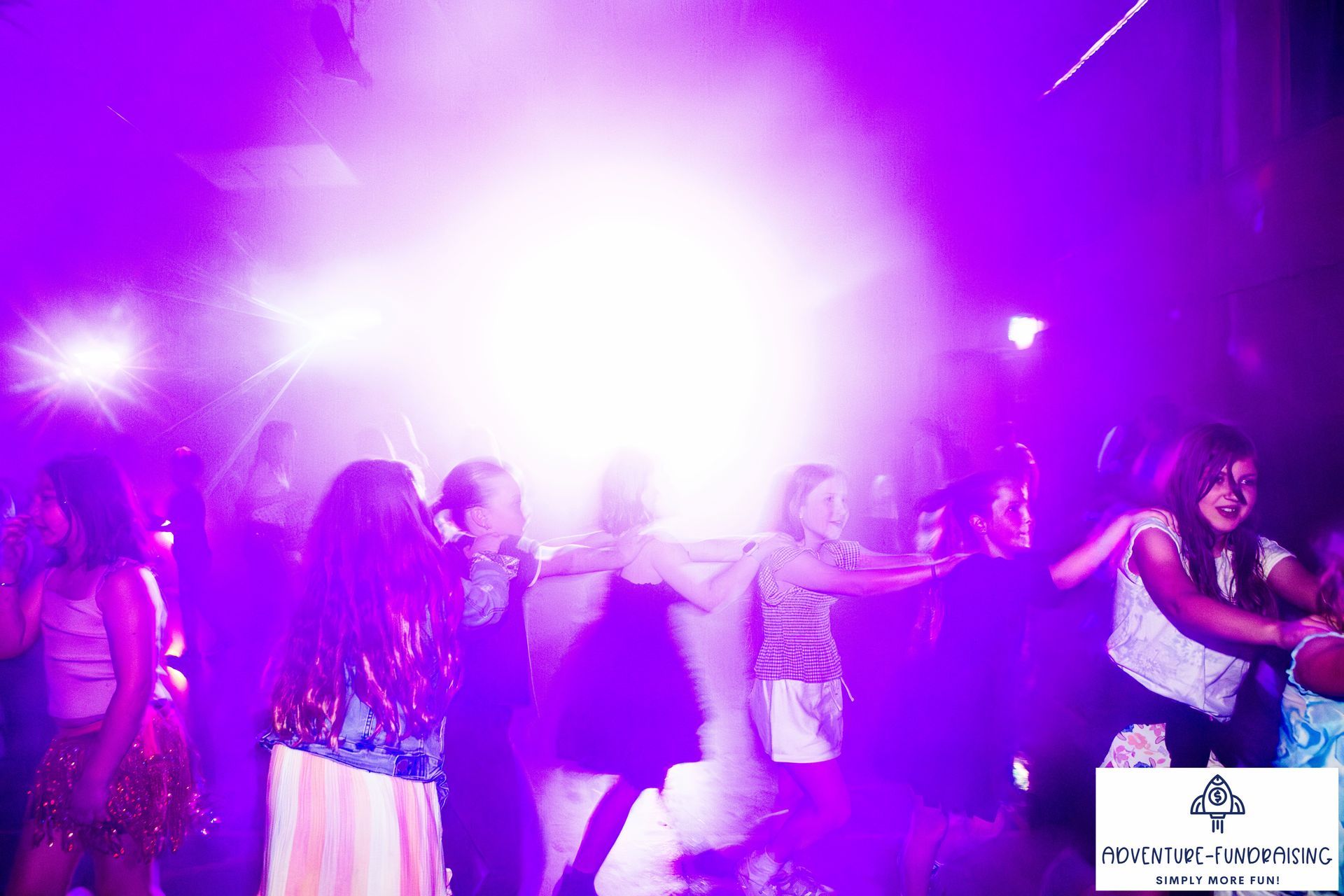Children dancing under purple stage lights.