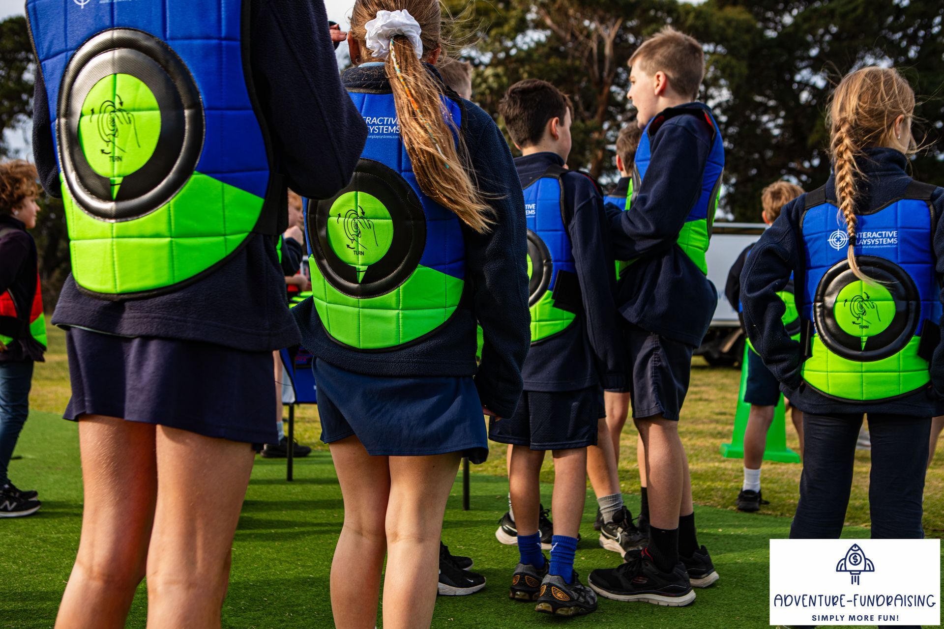 Children in blue and green vests with target designs stand outside.