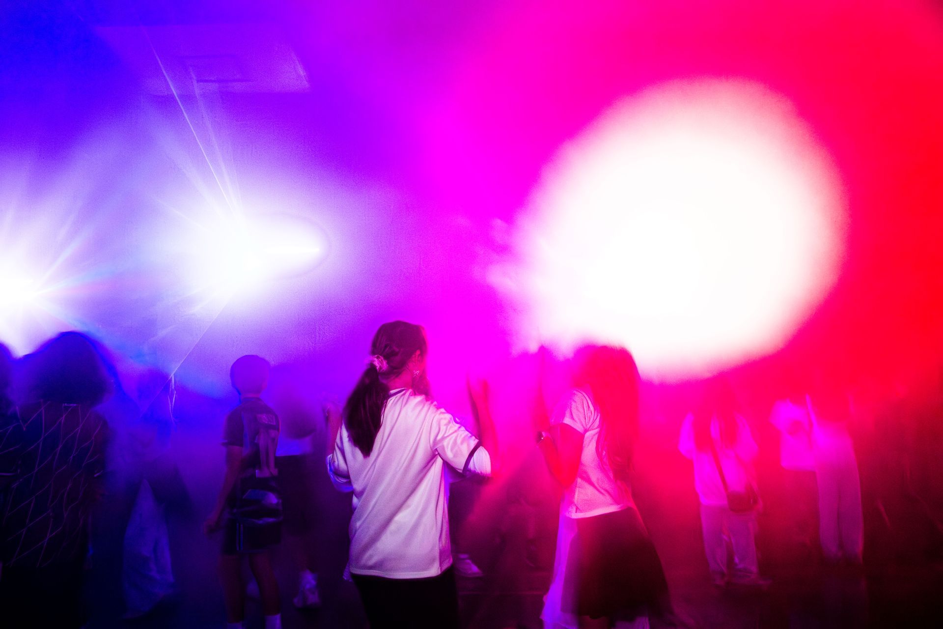People dancing in a club under blue, purple, and red stage lights.