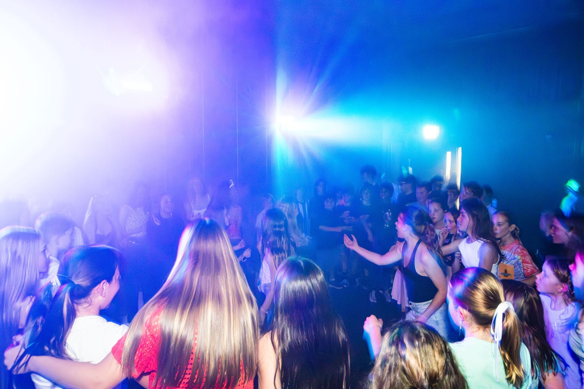 Dancing crowd under blue and white lights in a dark room.