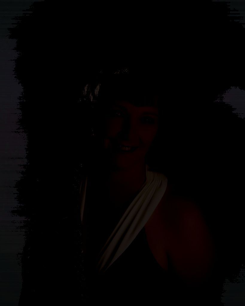 A woman in a black dress is smiling in the dark.