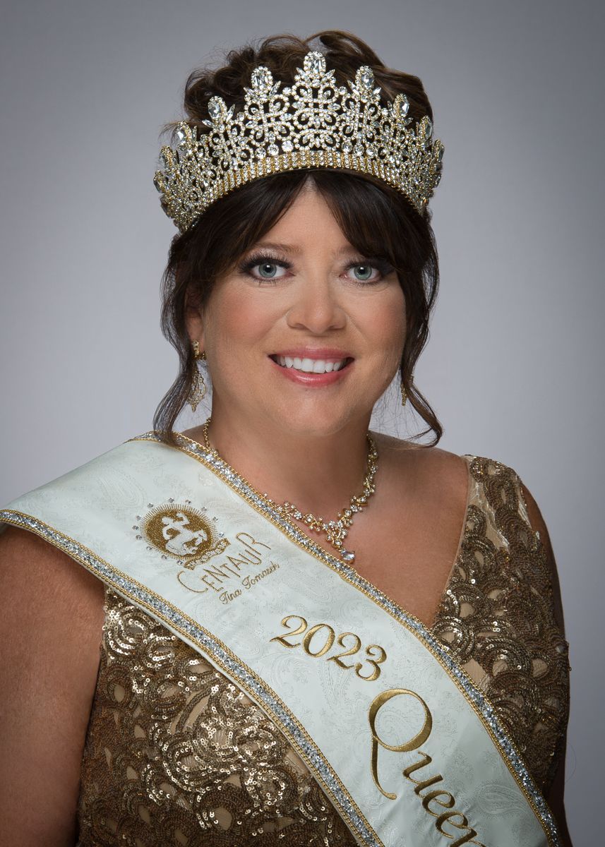 A woman is wearing a crown and sash and smiling.