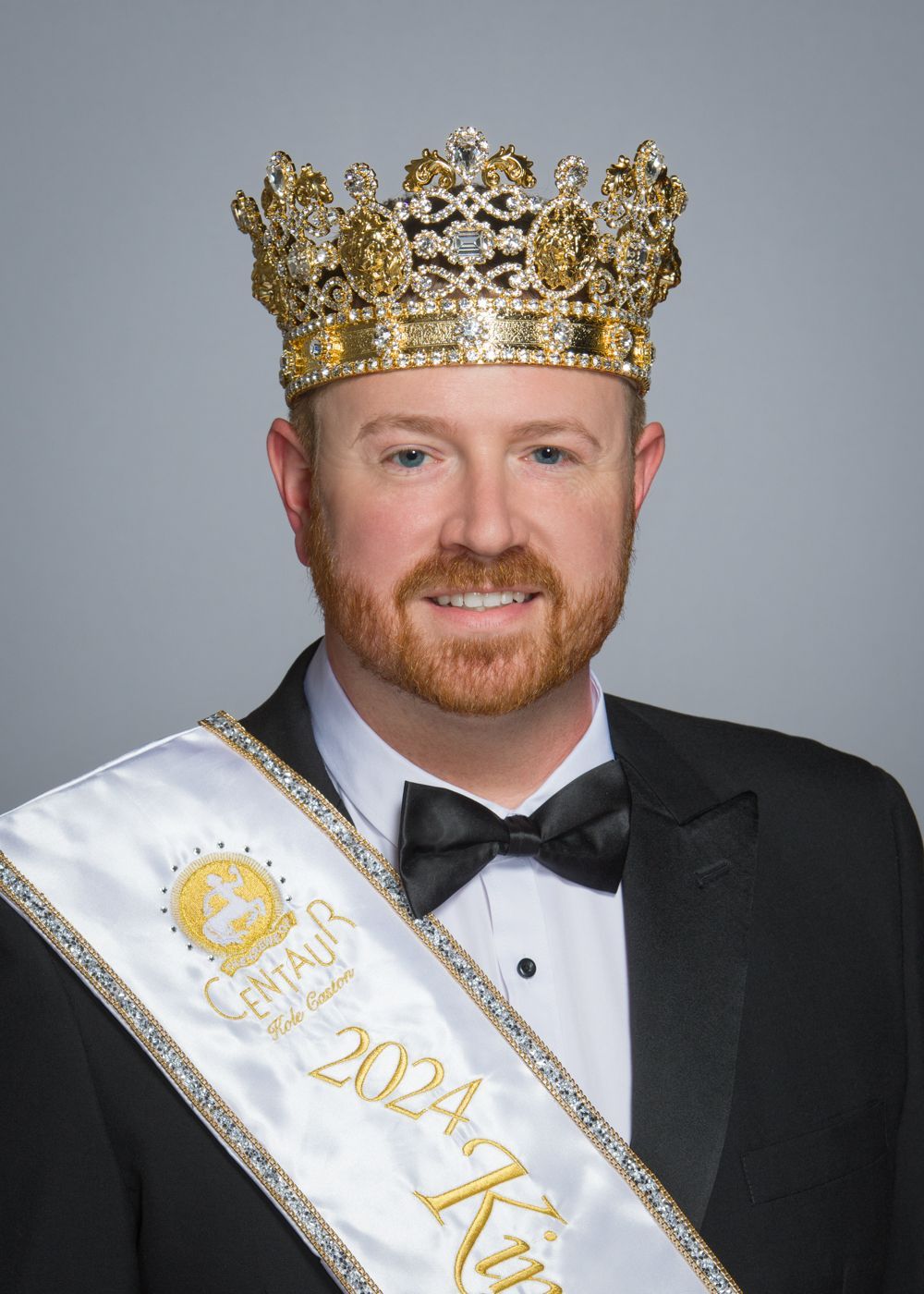 A man wearing a crown and a sash that says ' king ' on it.