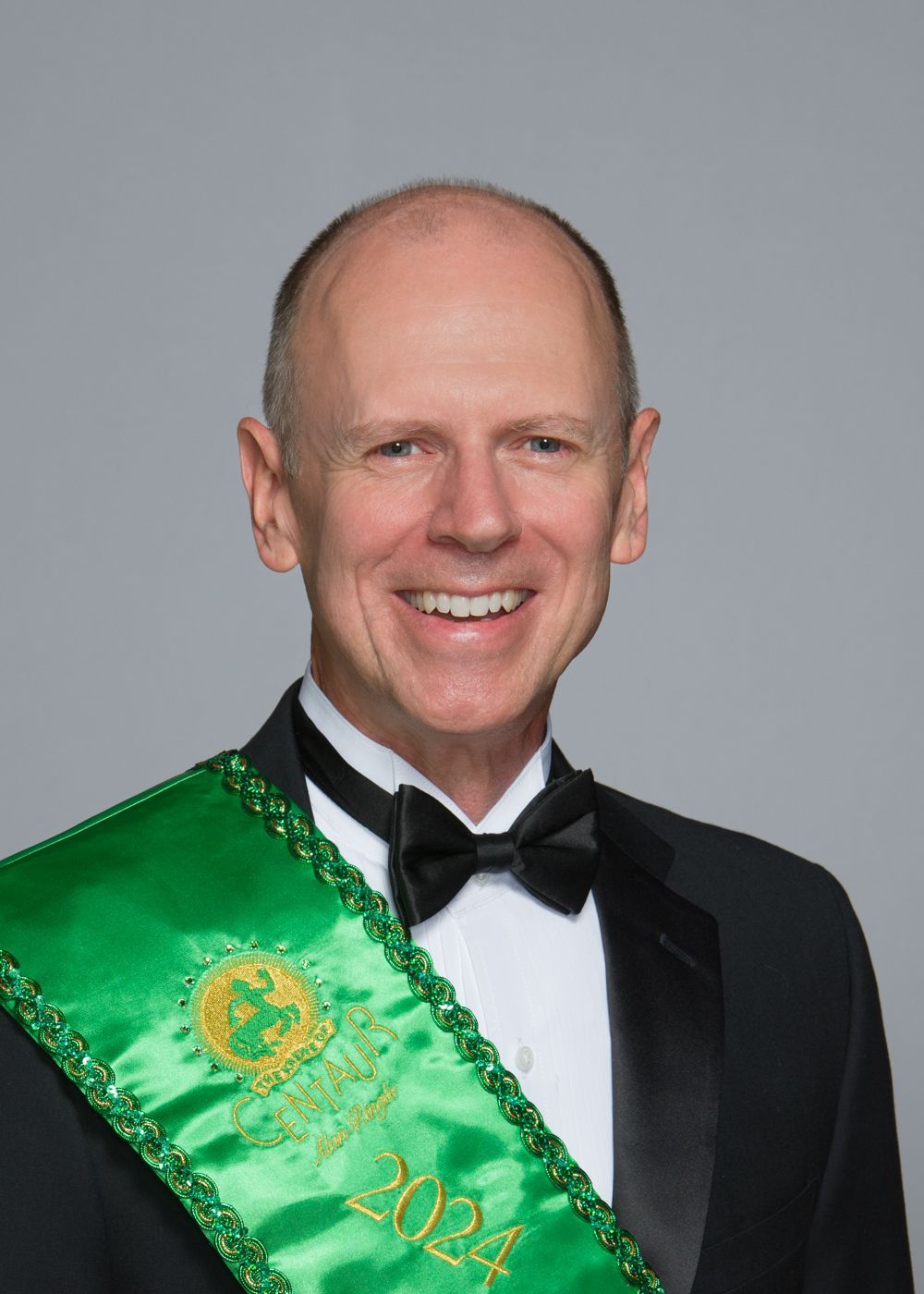 A man wearing a tuxedo and a green sash with the year 2024 on it