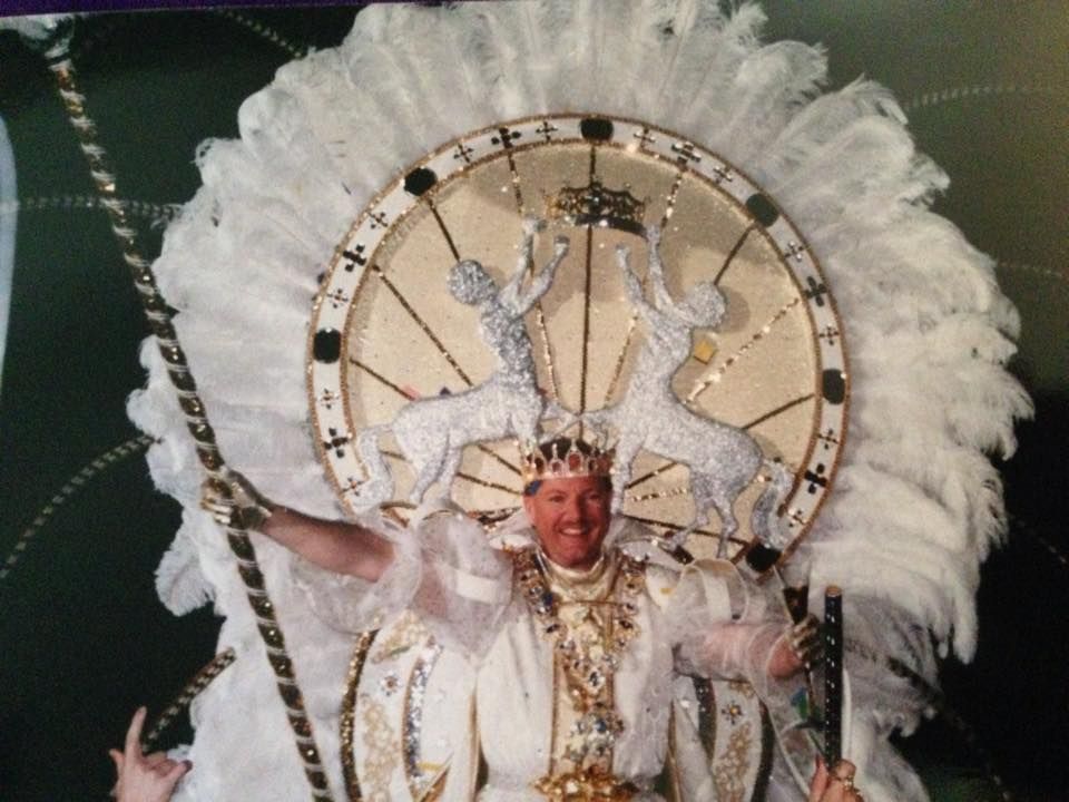 A man is wearing a feathered headdress and holding a cane