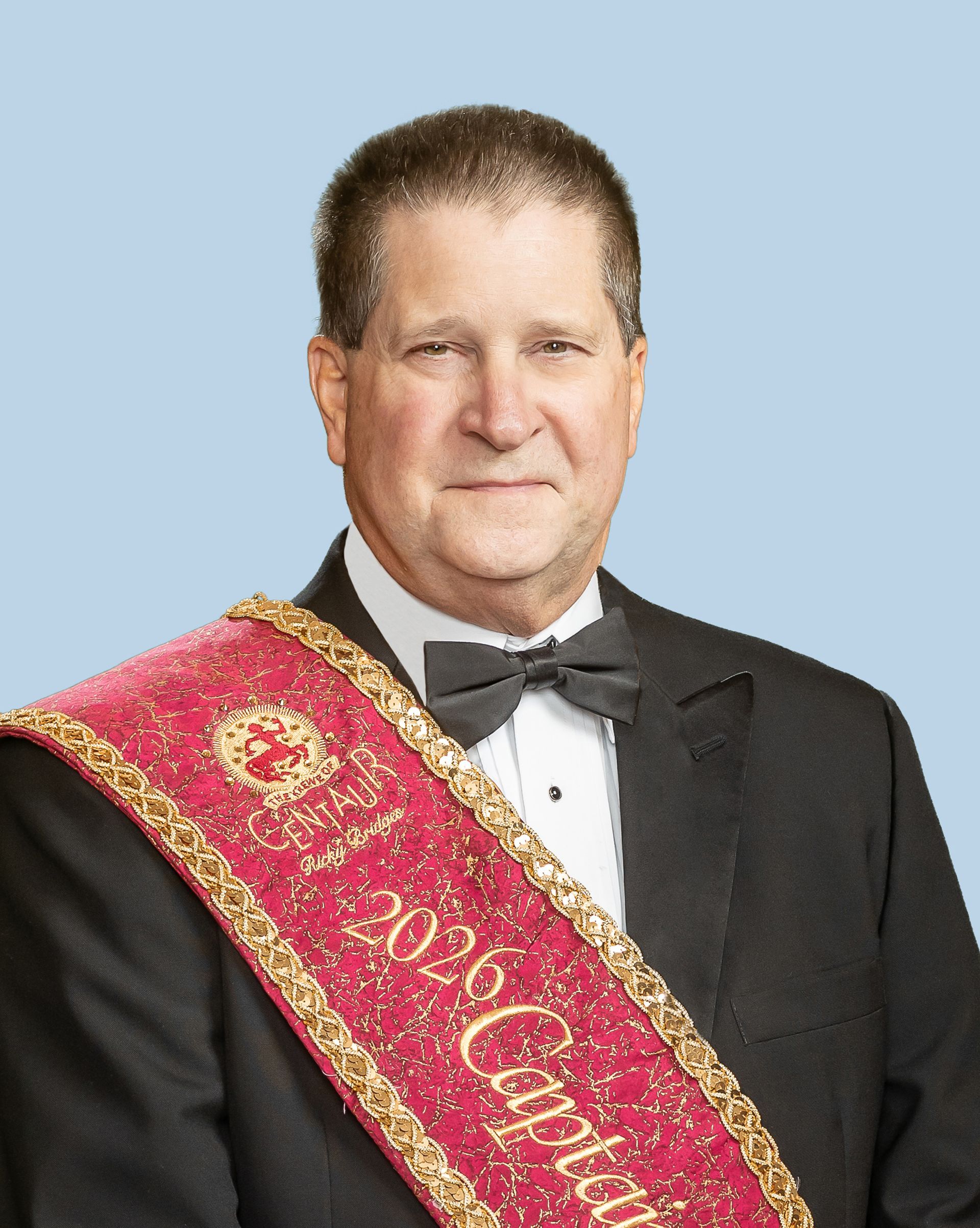 A man in a tuxedo is wearing a sash with the year 2025 on it.