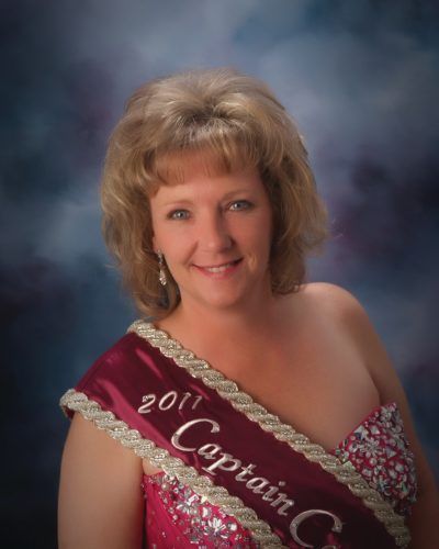 A woman is wearing a sash that says 2011 captain
