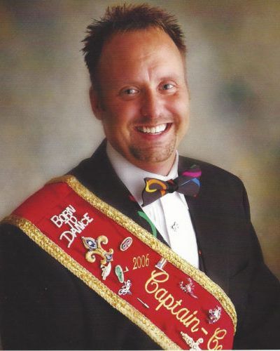 A man wearing a sash that says captain on it