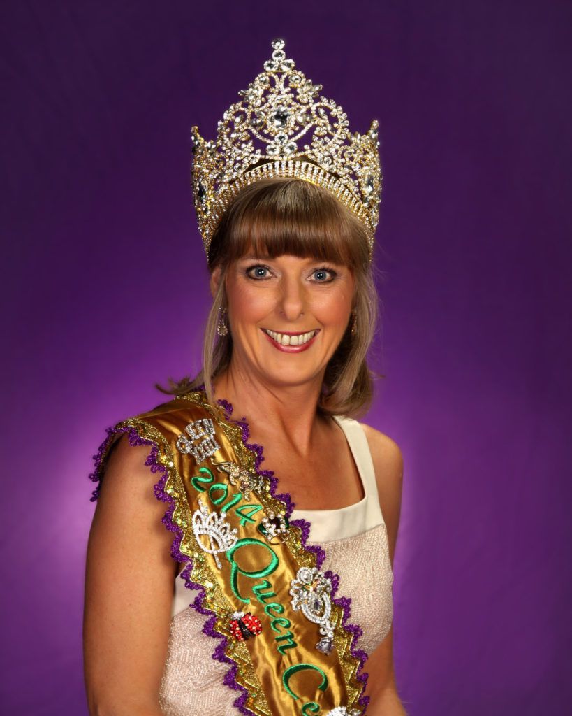 A woman wearing a crown and a sash that says mardi gras