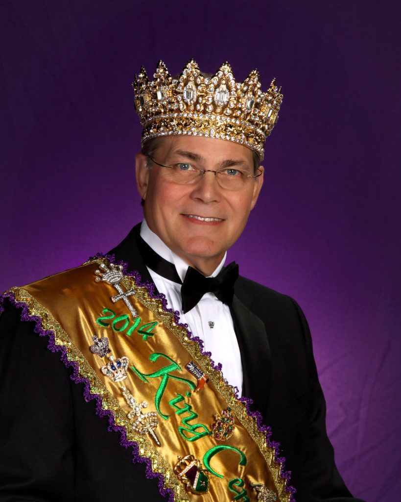 A man wearing a crown and a sash that says king