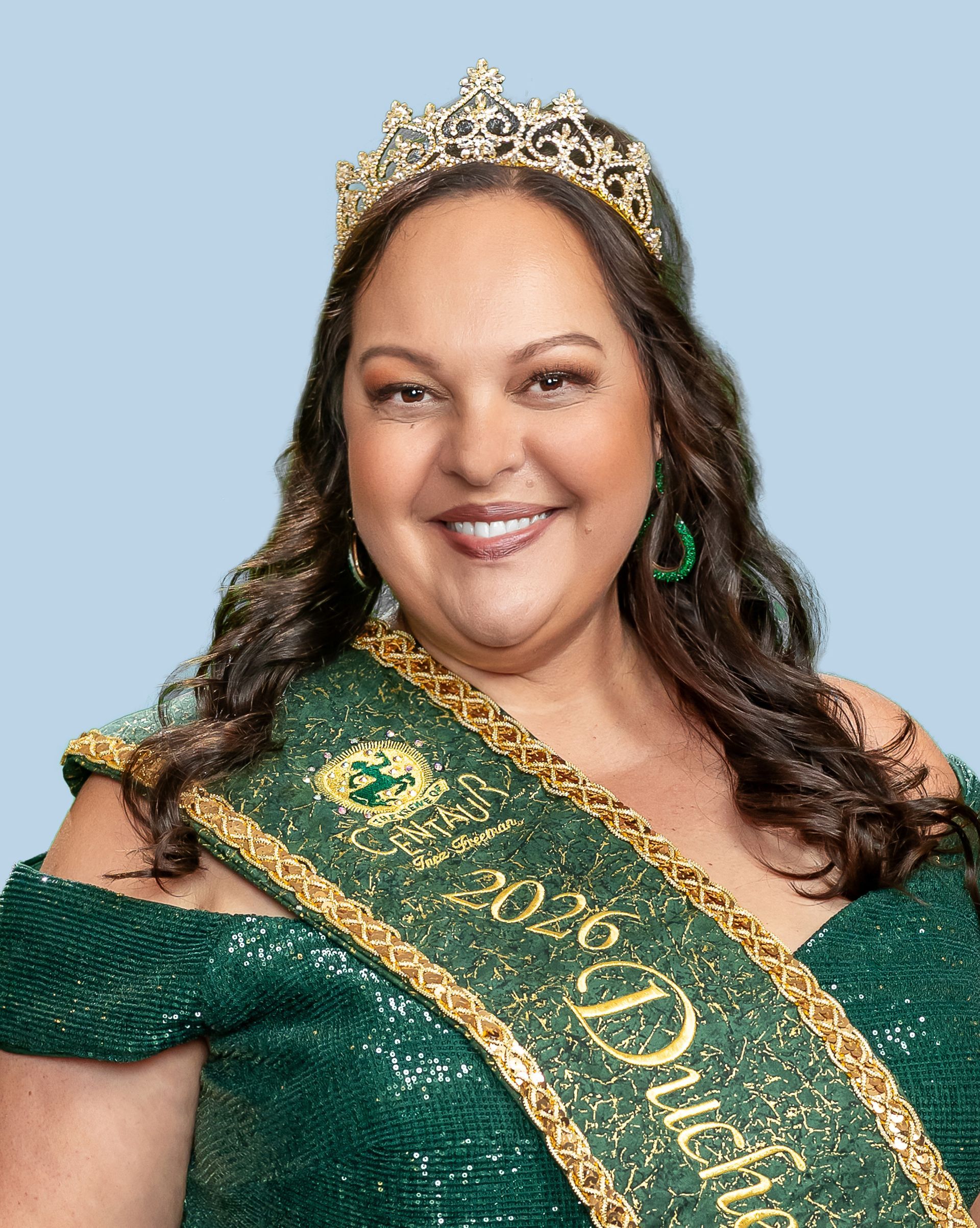 A woman is wearing a tiara and a green sash tha says duchess.