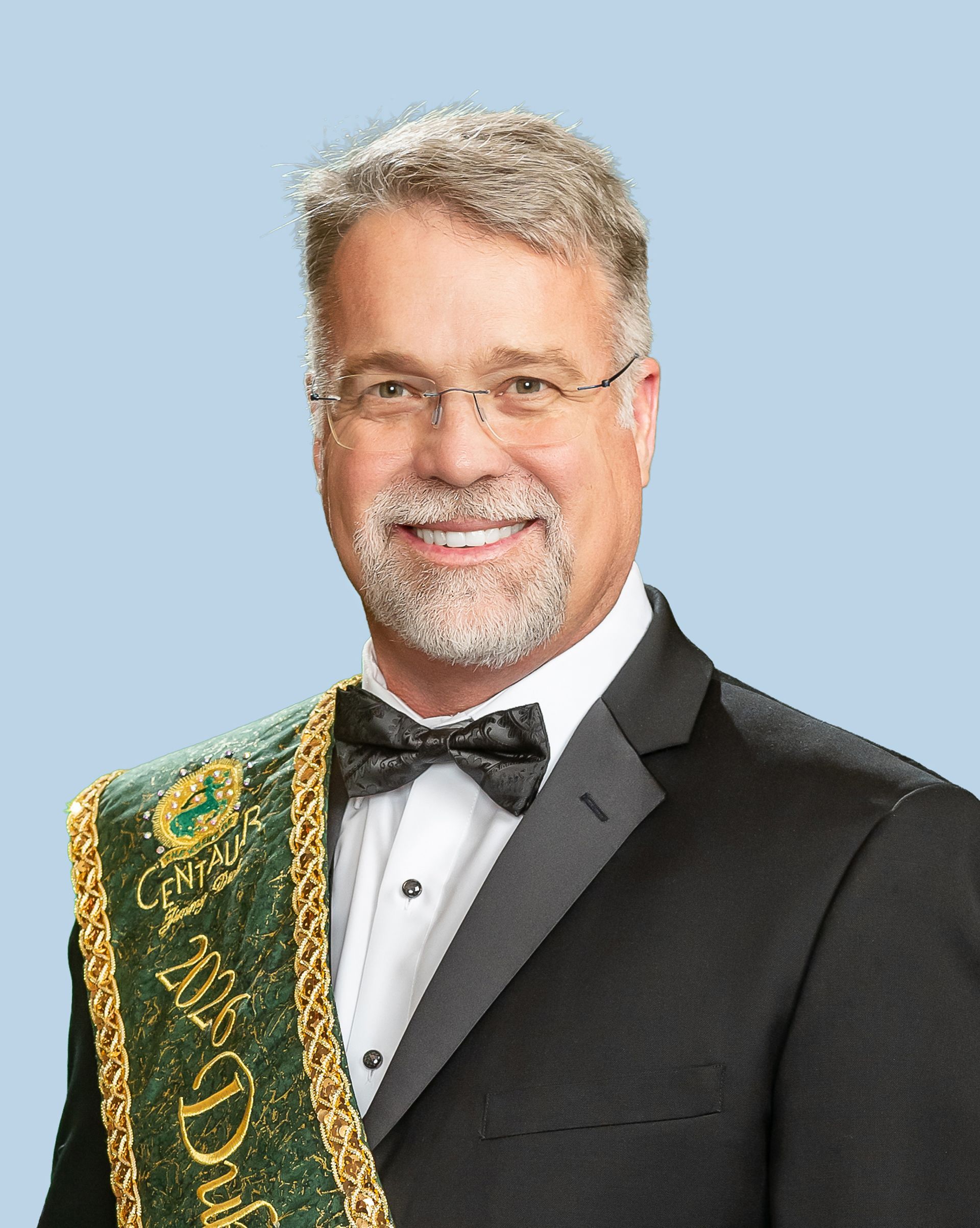 A man in a suit and bow tie is wearing a sash that says duke.