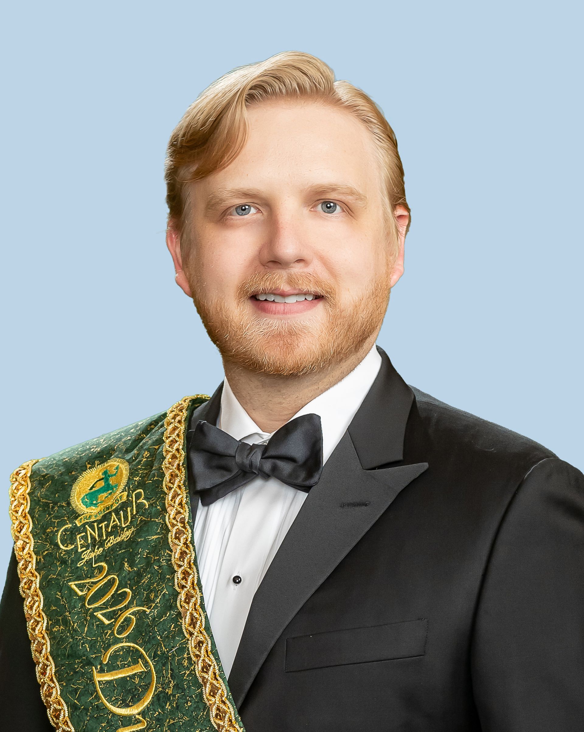 A man in a suit and bow tie is wearing a sash that says duke of