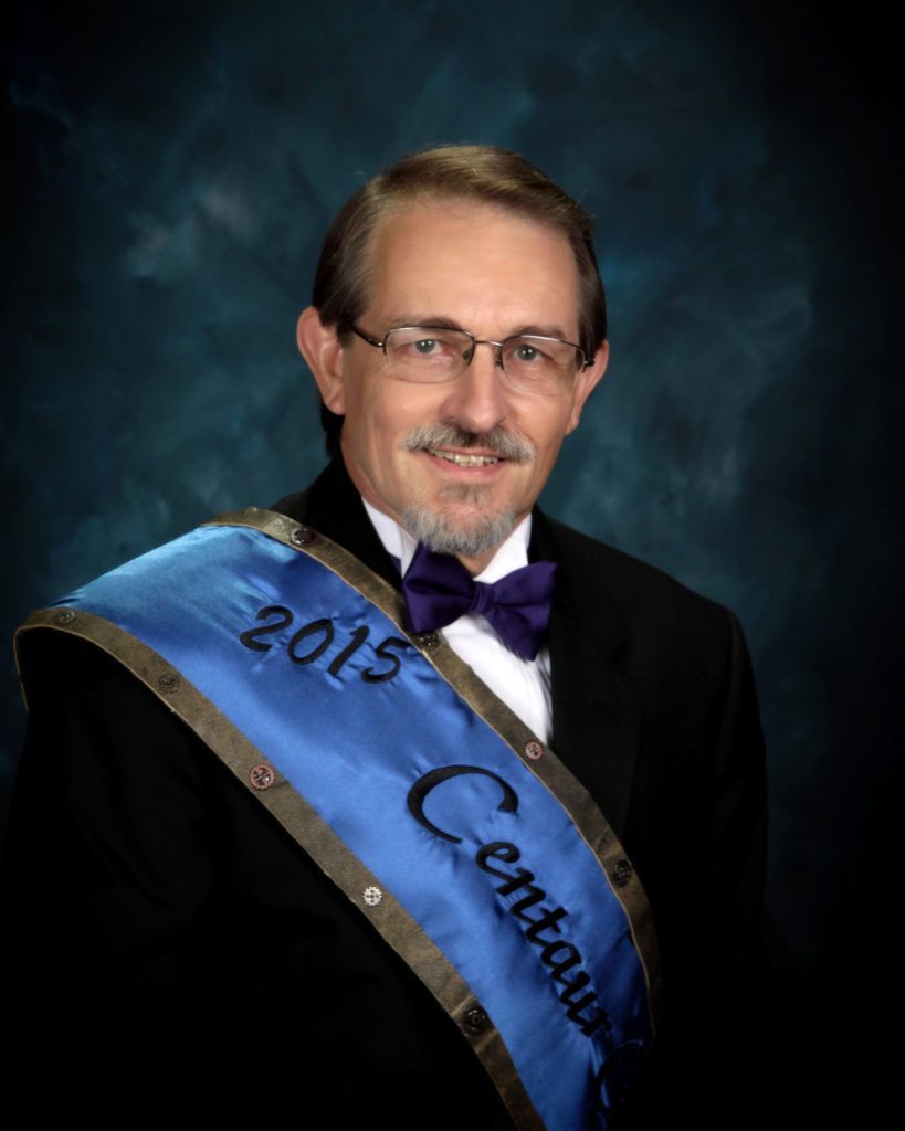 A man is wearing a sash that says 2015 centennial