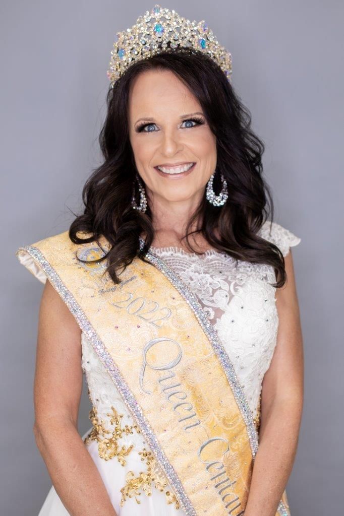 A woman in a white dress is wearing a tiara and sash.