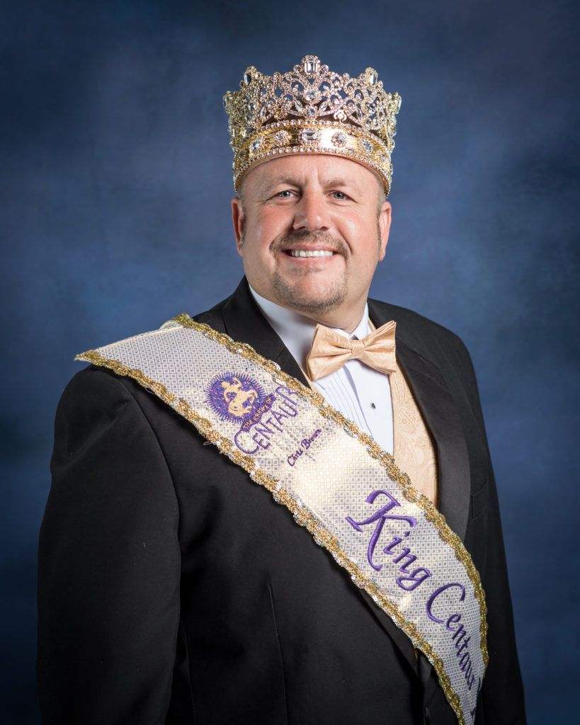 A man wearing a crown and a sash that says king