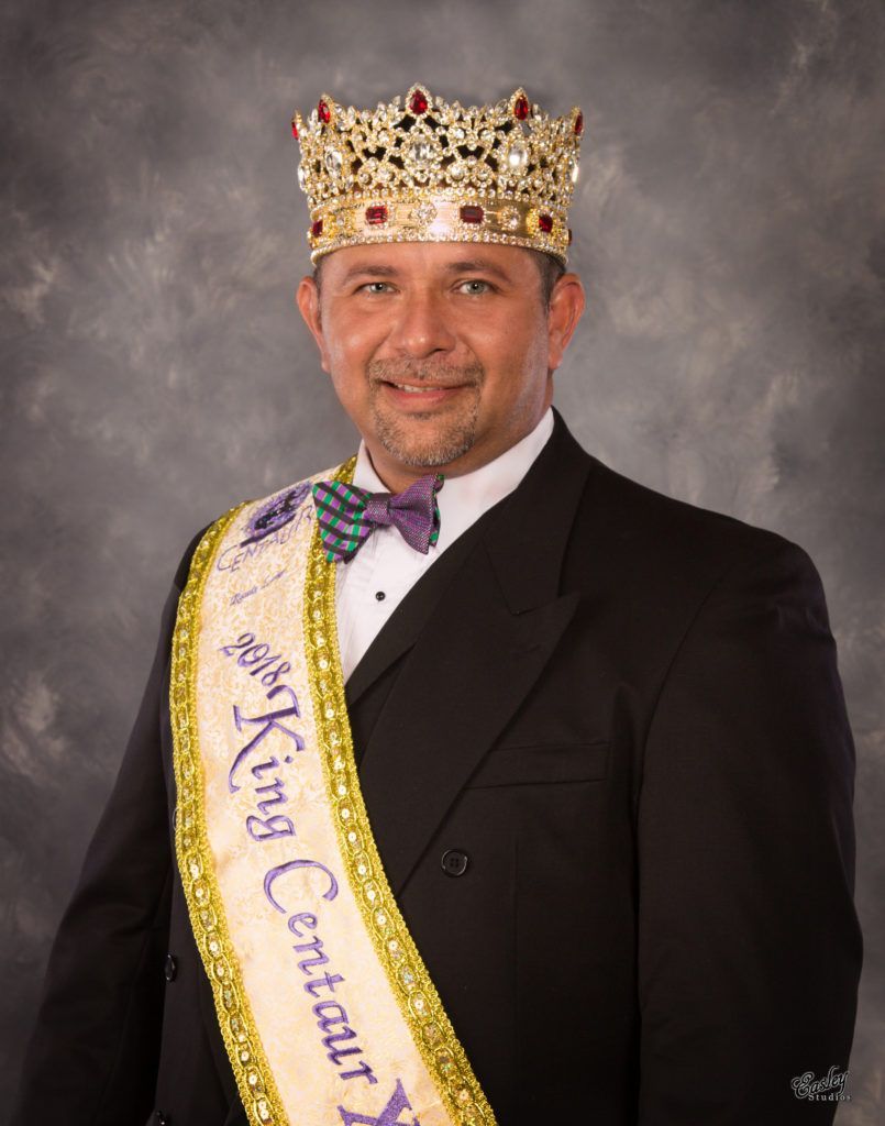A man wearing a crown and a sash that says king certain