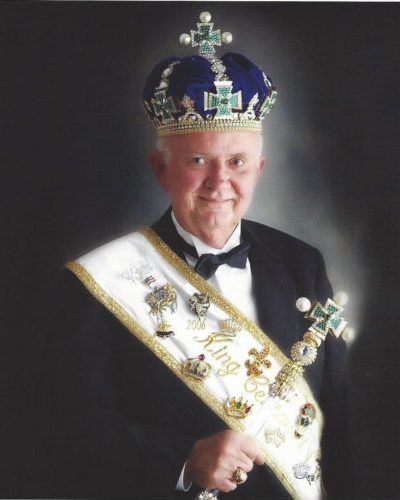A man wearing a crown and a sash that says ' king ' on it