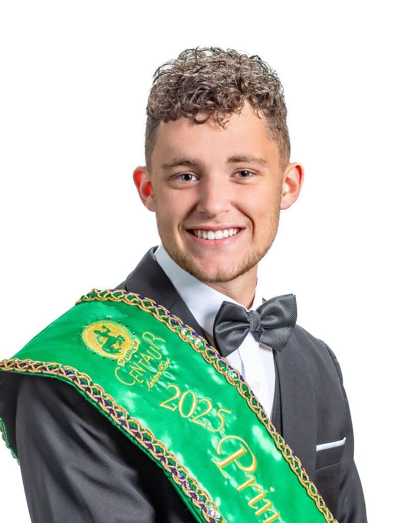 A young man in a suit and bow tie is wearing a green sash.