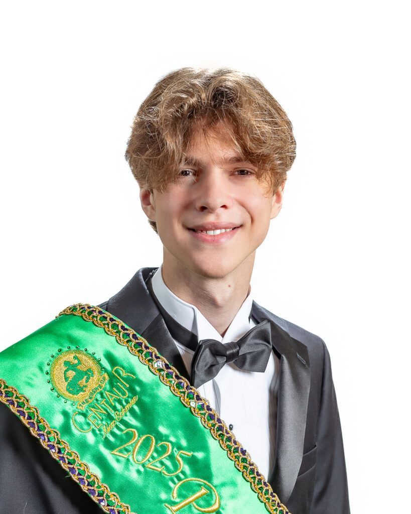 A young man in a tuxedo and bow tie is wearing a green sash.