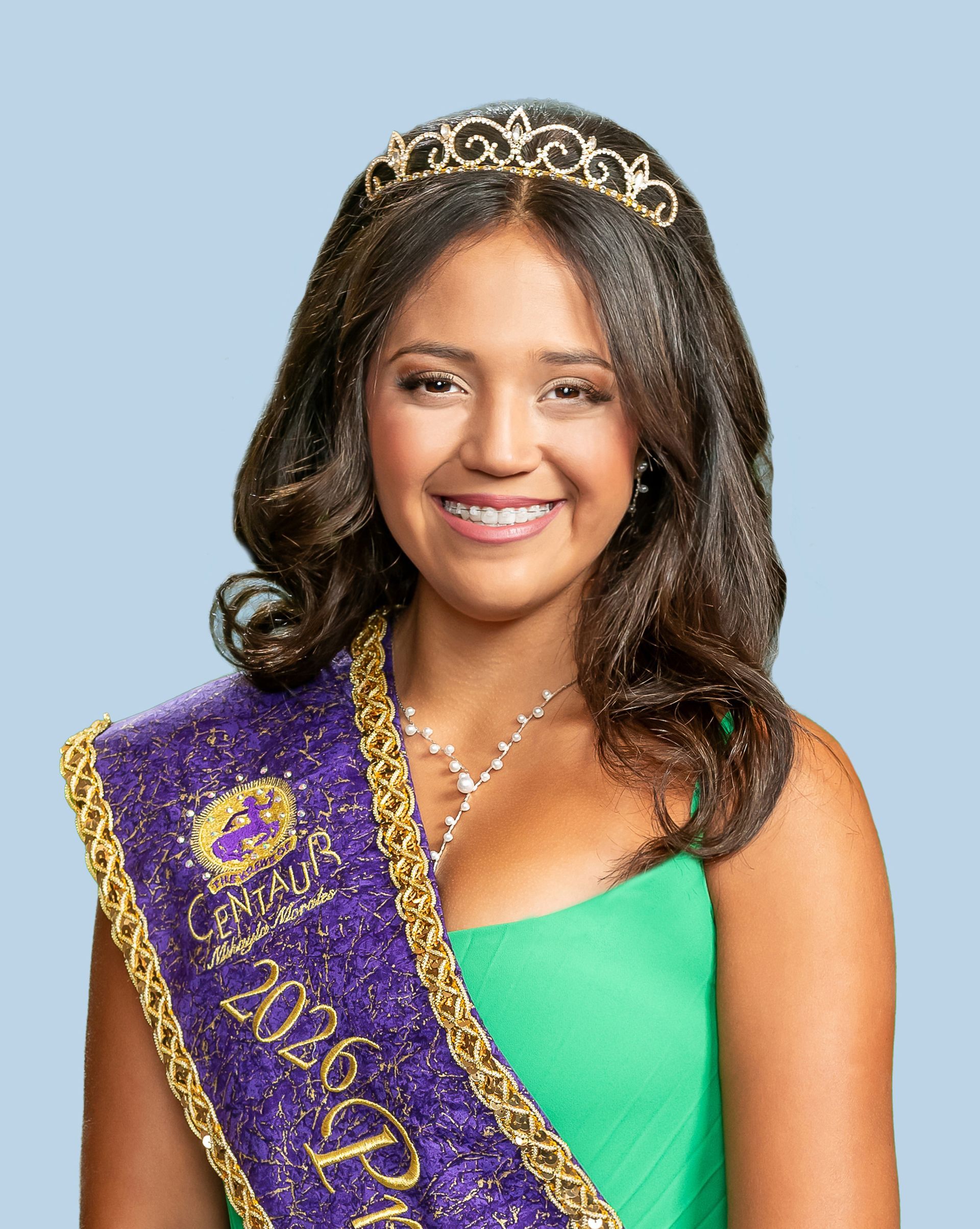 A woman wearing a purple sash and a tiara who is a princess. 