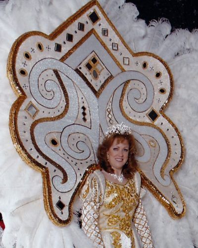 A woman in a white and gold costume with a crown on her head