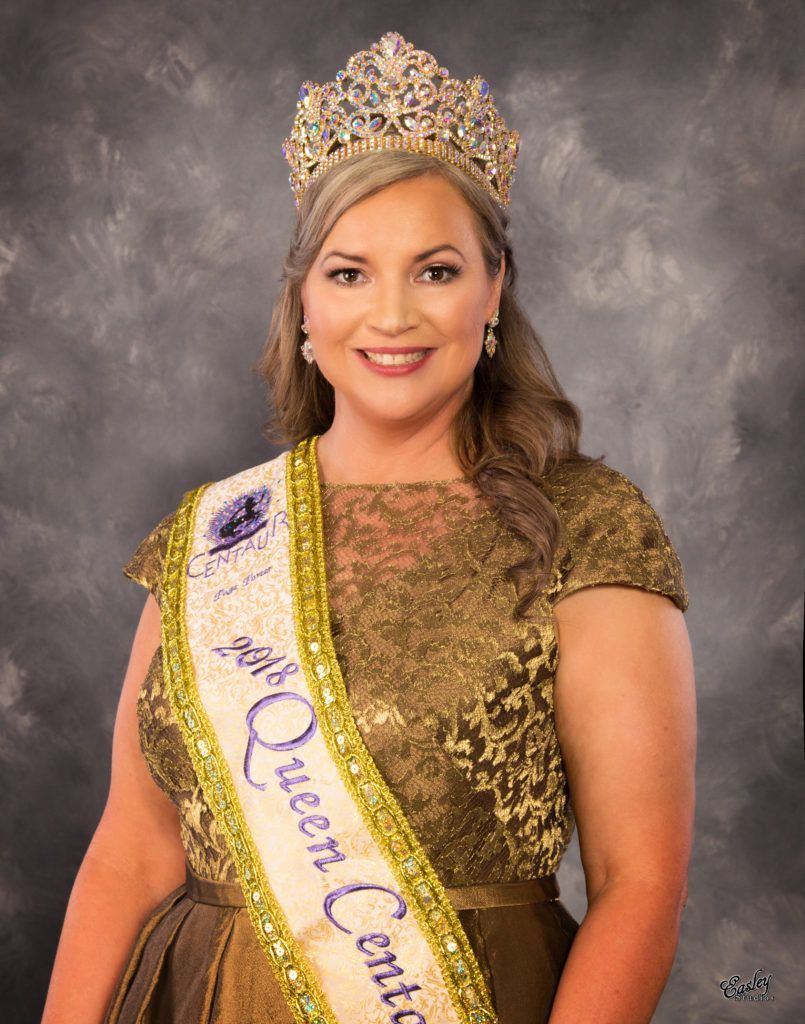 A woman is wearing a crown and a sash that says ' queen ' on it.