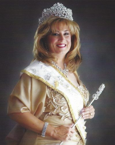 A woman wearing a tiara and sash is holding a wand