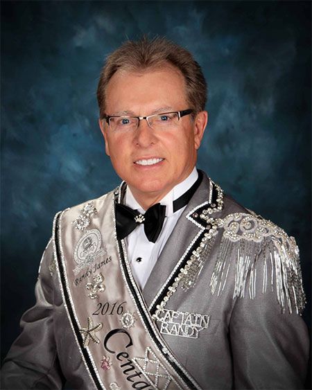 A man in a tuxedo is wearing a sash that says captain randy