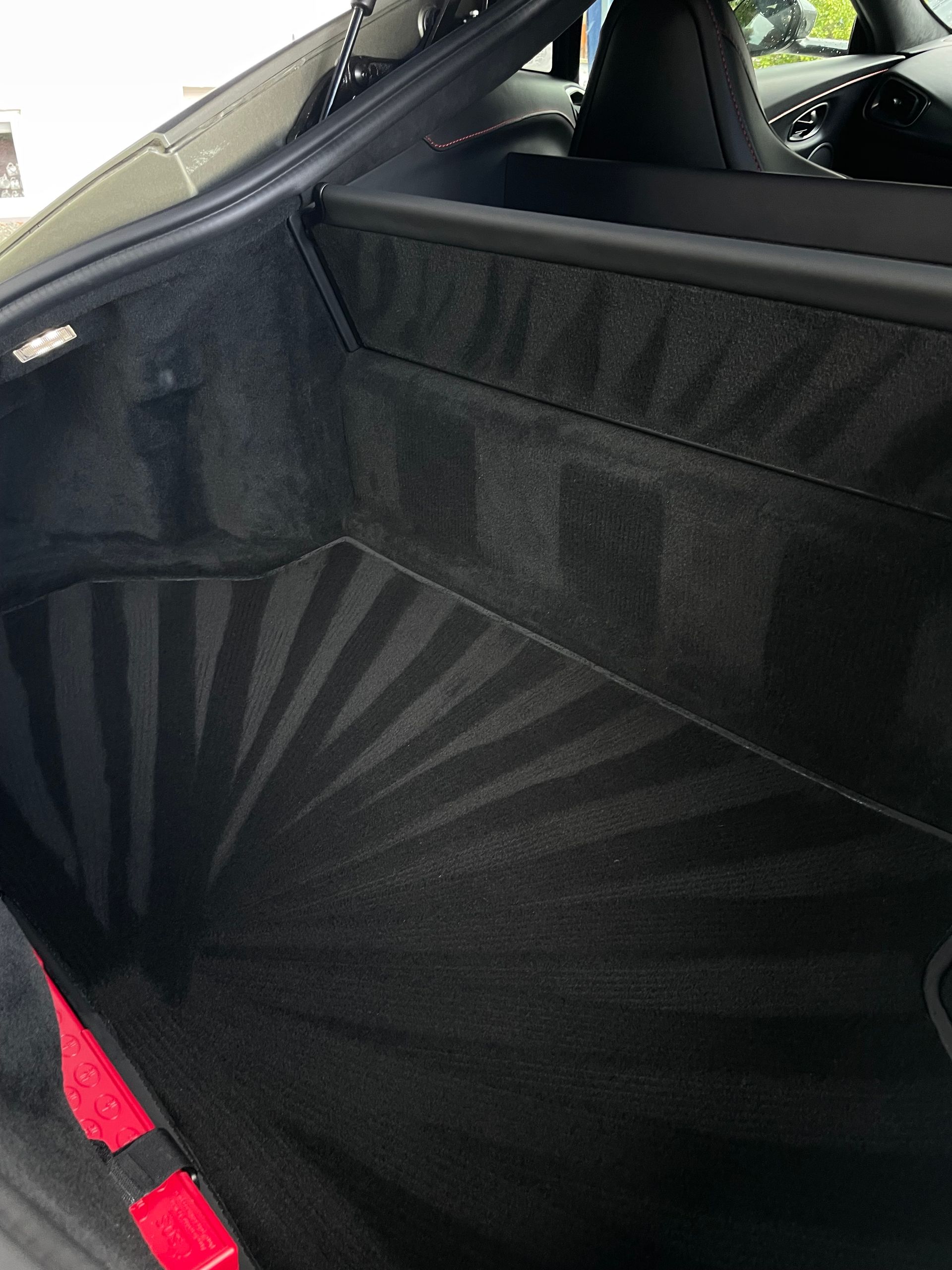 A view inside the carpeted trunk of a vehicle, featuring a sunburst pattern vacuumed into the floor mat.