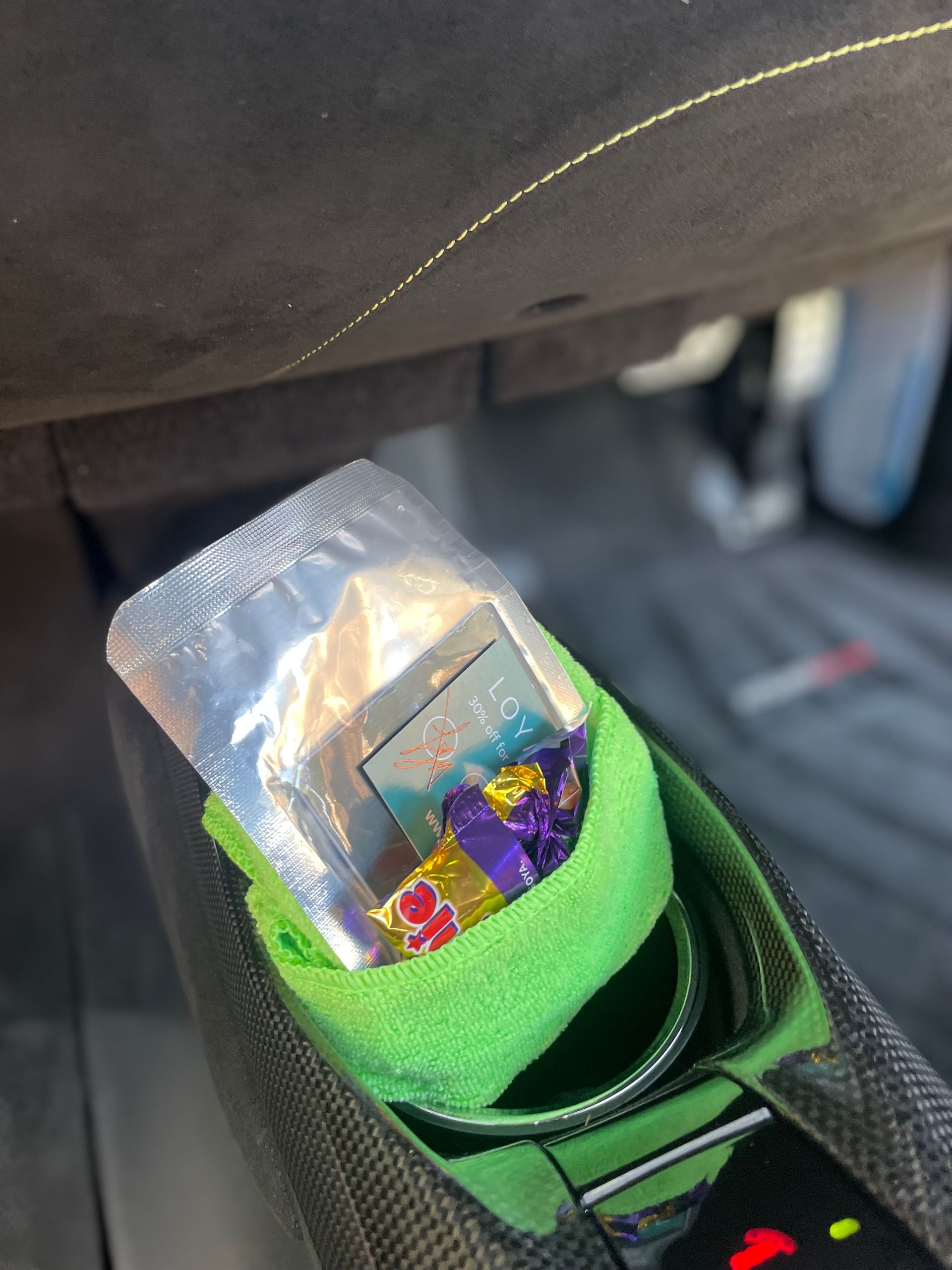 A partially open silver foil packet containing a small purple and yellow candy inside a bright green shoe.